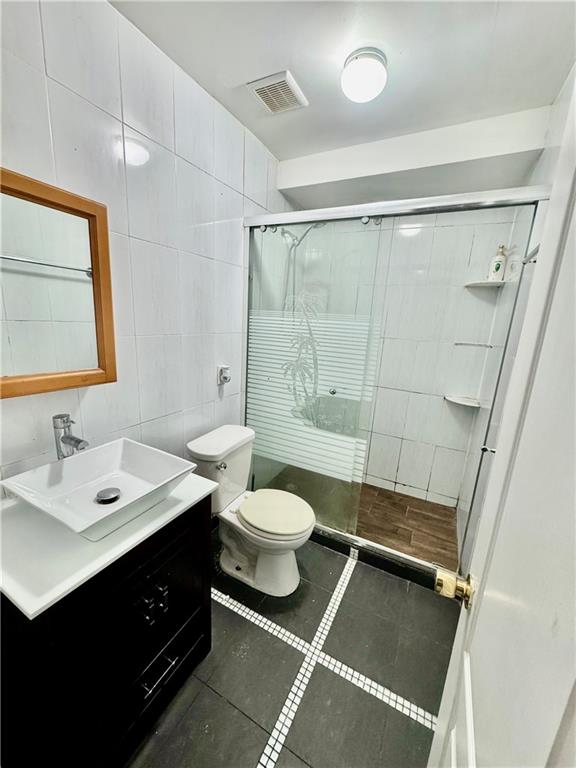1476 67th Street, Unit 1 Brooklyn, NY 11219 - Photo 5 of 6 a bathroom with a double vanity sink toilet mirror and shower