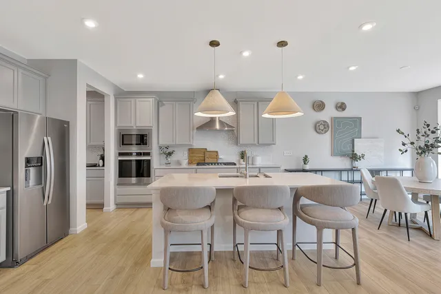 a kitchen with stainless steel appliances granite countertop a kitchen island hardwood floor and chairs