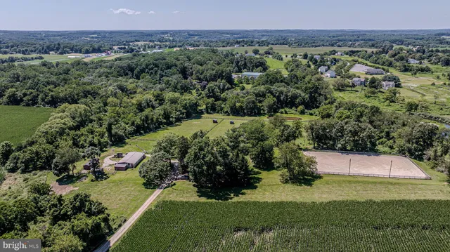 an aerial view of a houses with outdoor space and trees all around