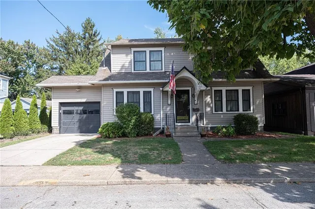 a front view of a house with a yard and potted plants