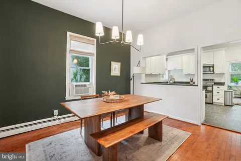 a dining room with wooden floor and kitchen view