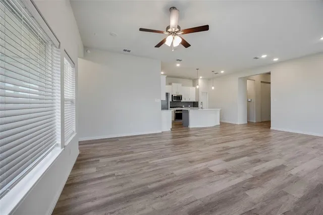 a view of a kitchen with a ceiling fan hardwood floor and a ceiling fan