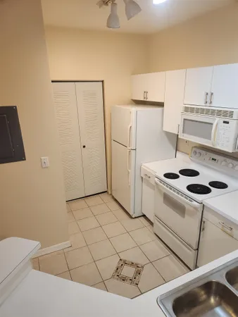 a kitchen with a white stove top oven and white countertops with wooden floor
