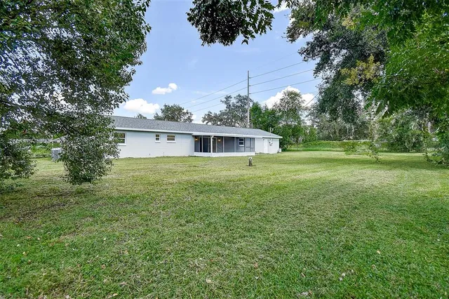 a white house with a big yard and large trees