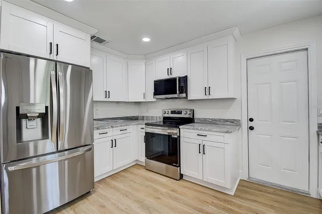 a kitchen with cabinets stainless steel appliances and a wooden floor