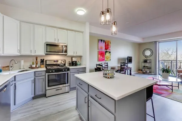 a kitchen with a stove a sink dishwasher and a refrigerator with wooden floor