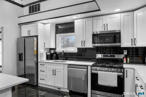 a kitchen with stainless steel appliances granite countertop a stove a sink and a refrigerator