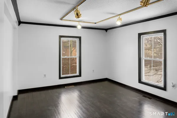 a view of an empty room with wooden floor and a window