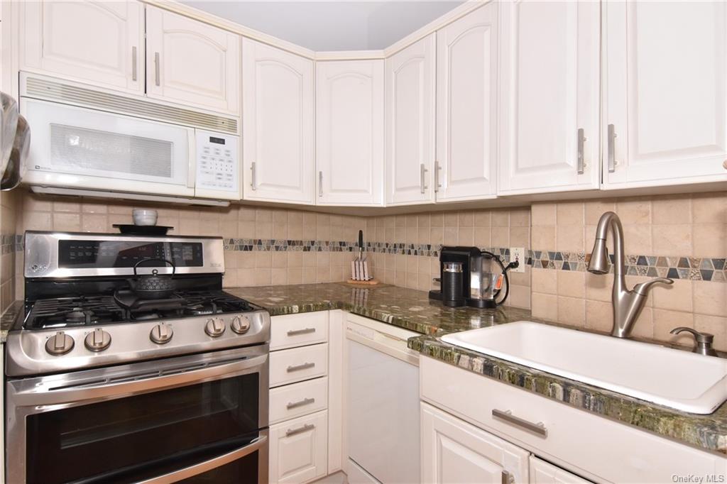 a kitchen with granite countertop a stove a sink and dishwasher wooden cabinets