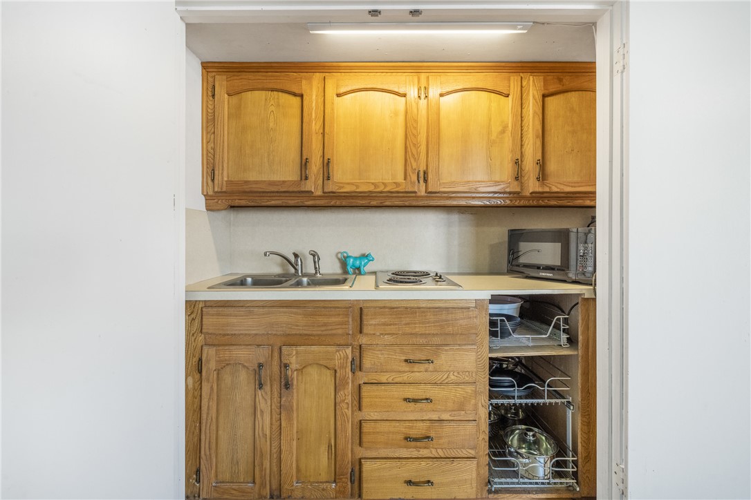 909 Enfield Street Bryan, TX 77802 - Photo 31 of 45 Kitchenette in additional living room nicely tucked away in a closet with warm wood cabinets, sink, burner and microwave.