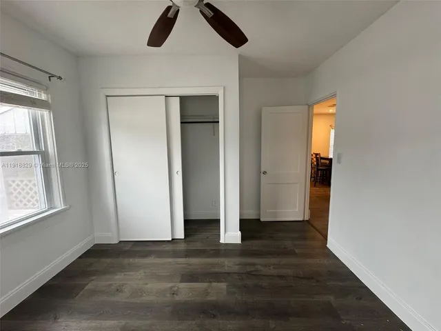 an empty room with wooden floor cabinet and windows