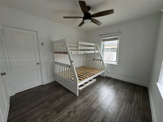a view of a livingroom with wooden floor a ceiling fan and windows