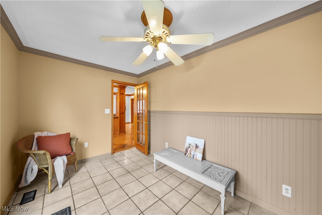 4819 Westbourne Road Cleveland, OH 44124 - Photo 19 of 39 Sitting room featuring a wainscoted wall, crown molding, light tile patterned floors, and a ceiling fan