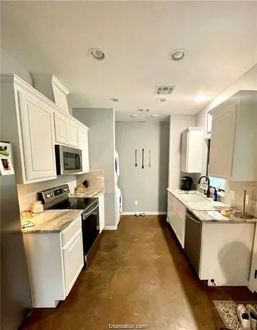 a large kitchen with a stove top oven a sink a counter space and cabinets