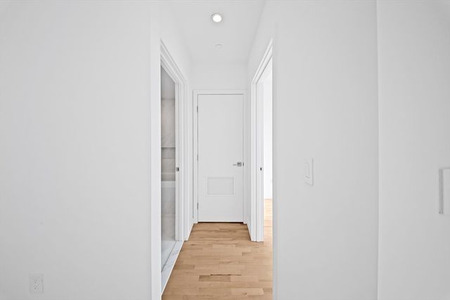 a view of a hallway with wooden floor and closet