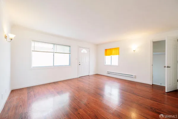 a view of empty room with wooden floor and fan
