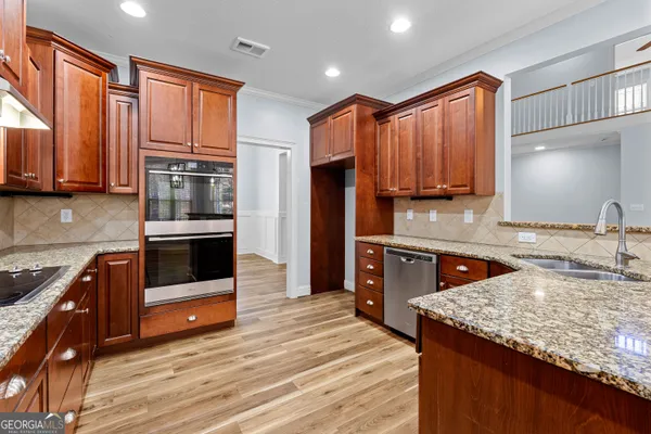 a large kitchen with stainless steel appliances granite countertop a sink and a refrigerator