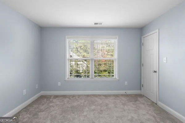 an empty room with a chandelier fan and windows