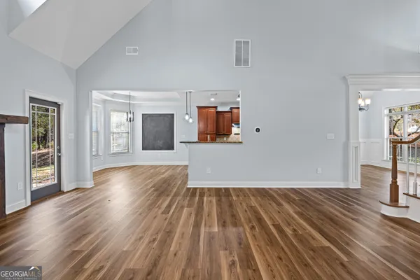 a view of an empty room with wooden floor and windows