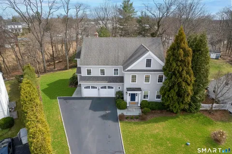 a aerial view of a house next to a yard with plants and large trees