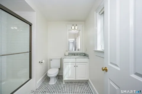 a bathroom with a sink a toilet a shower and a window