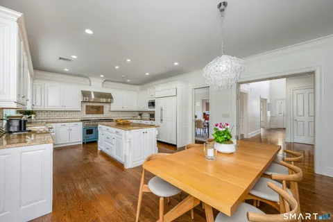 a large kitchen with kitchen island a stove a sink a refrigerator and a dining table with wooden floor