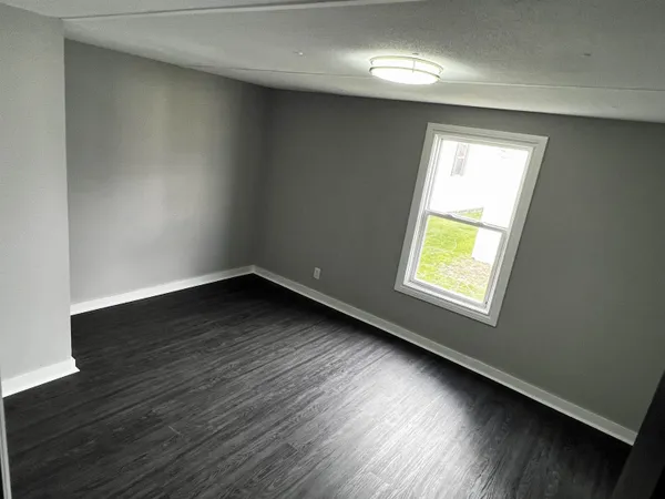 a view of an empty room with wooden floor and closet