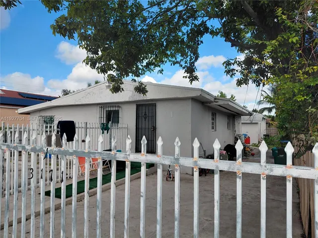 a view of a house with wooden deck and a large tree