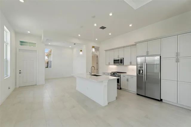 a kitchen with stainless steel appliances kitchen island a refrigerator and white cabinets