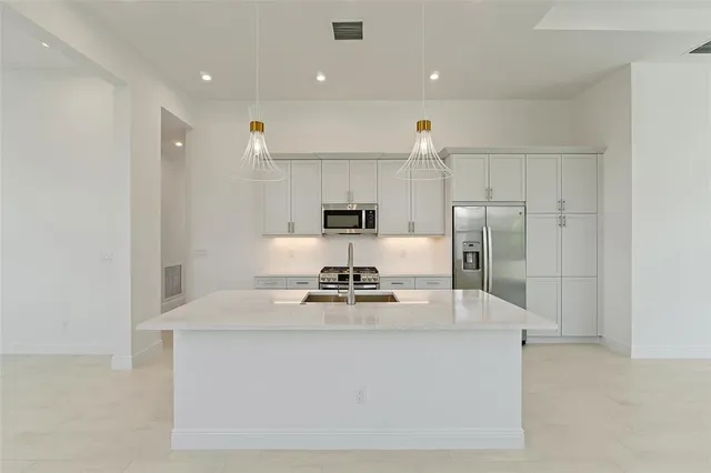 a kitchen with kitchen island a sink stainless steel appliances and cabinets