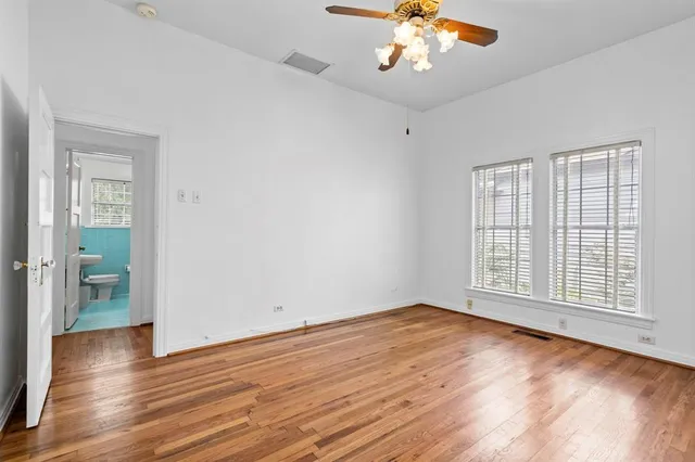 an empty room with wooden floor chandelier and windows