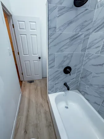 a bathroom with a tub a sink and wooden floor