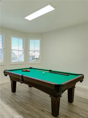 a room with wooden floor pool table and chairs