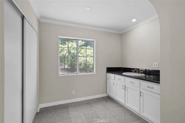 a kitchen with granite countertop a stove a sink and white cabinets with wooden floor