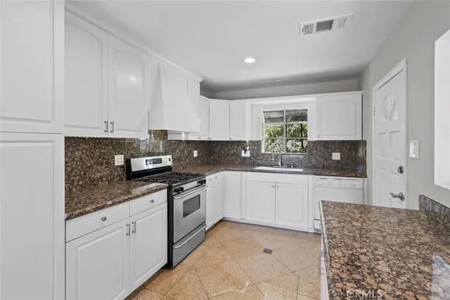 a kitchen with stainless steel appliances granite countertop a stove sink and cabinets
