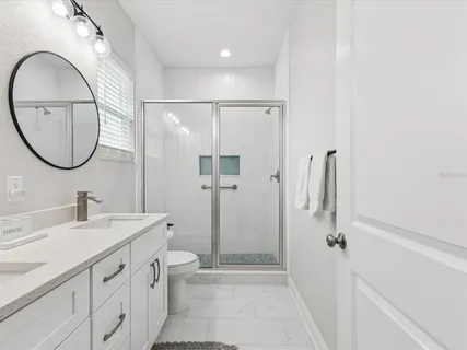 a spacious bathroom with a double vanity sink a toilet and a mirror