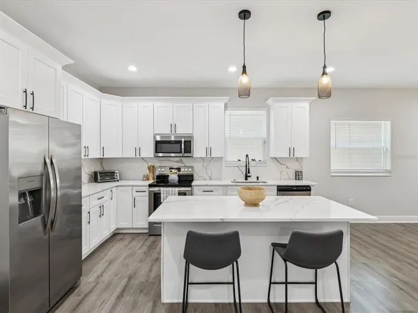 a kitchen with stainless steel appliances granite countertop a sink a stove a dining table and chairs