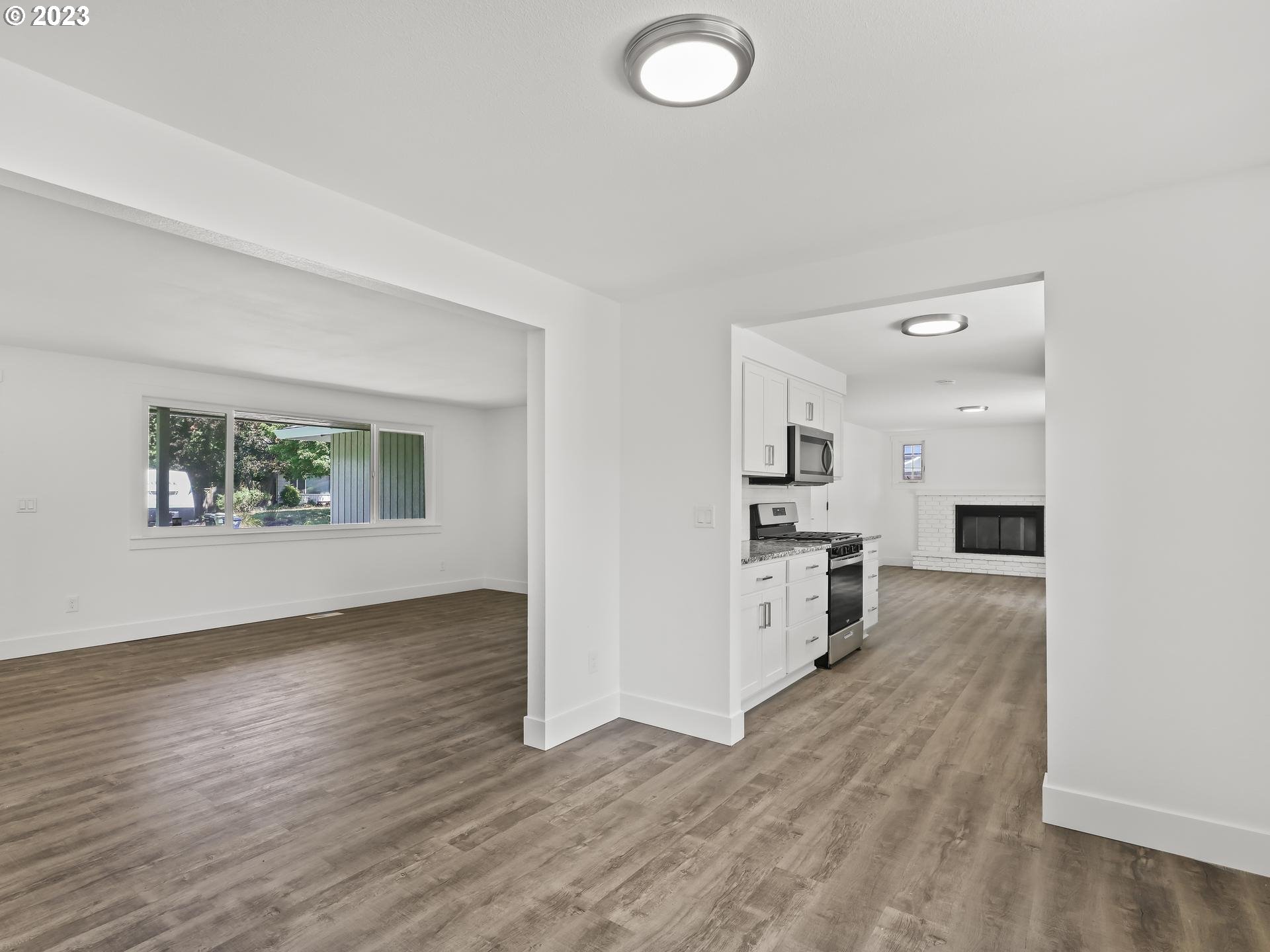 19650 Southwest Celebrity Street Beaverton, OR 97078 - Photo 6 of 47 an empty room with wooden floor and a kitchen