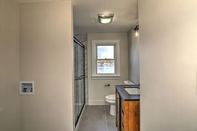 a bathroom with a toilet a sink a mirror and a window