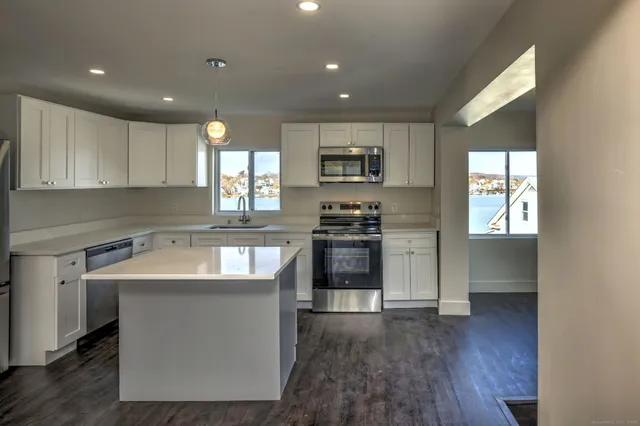 a kitchen with kitchen island white cabinets appliances and a sink