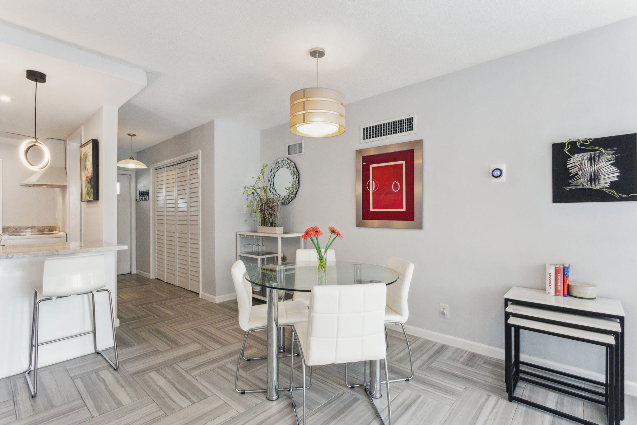 698 Northeast Spanish River Boulevard, Unit 24 Boca Raton, FL 33431 - Photo 9 of 25 a dining room with wooden floor a chandelier a wooden table and chairs