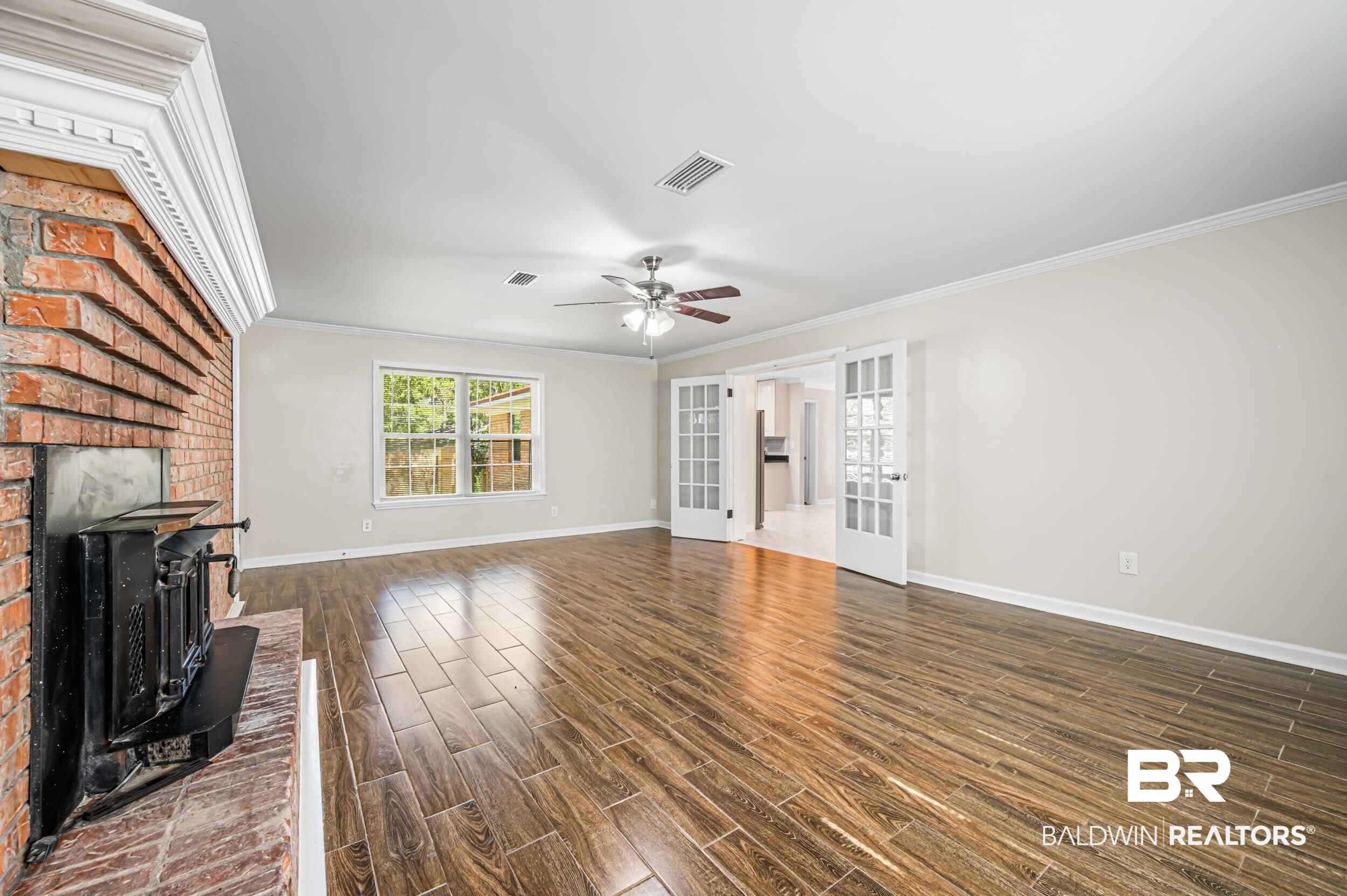 1605 Collier Avenue Bay Minette, AL 36507 - Photo 12 of 36 Unfurnished living room featuring crown molding, wood tiled floors, a wood stove, and french doors