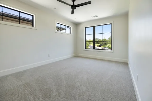 an empty room with windows and ceiling fan