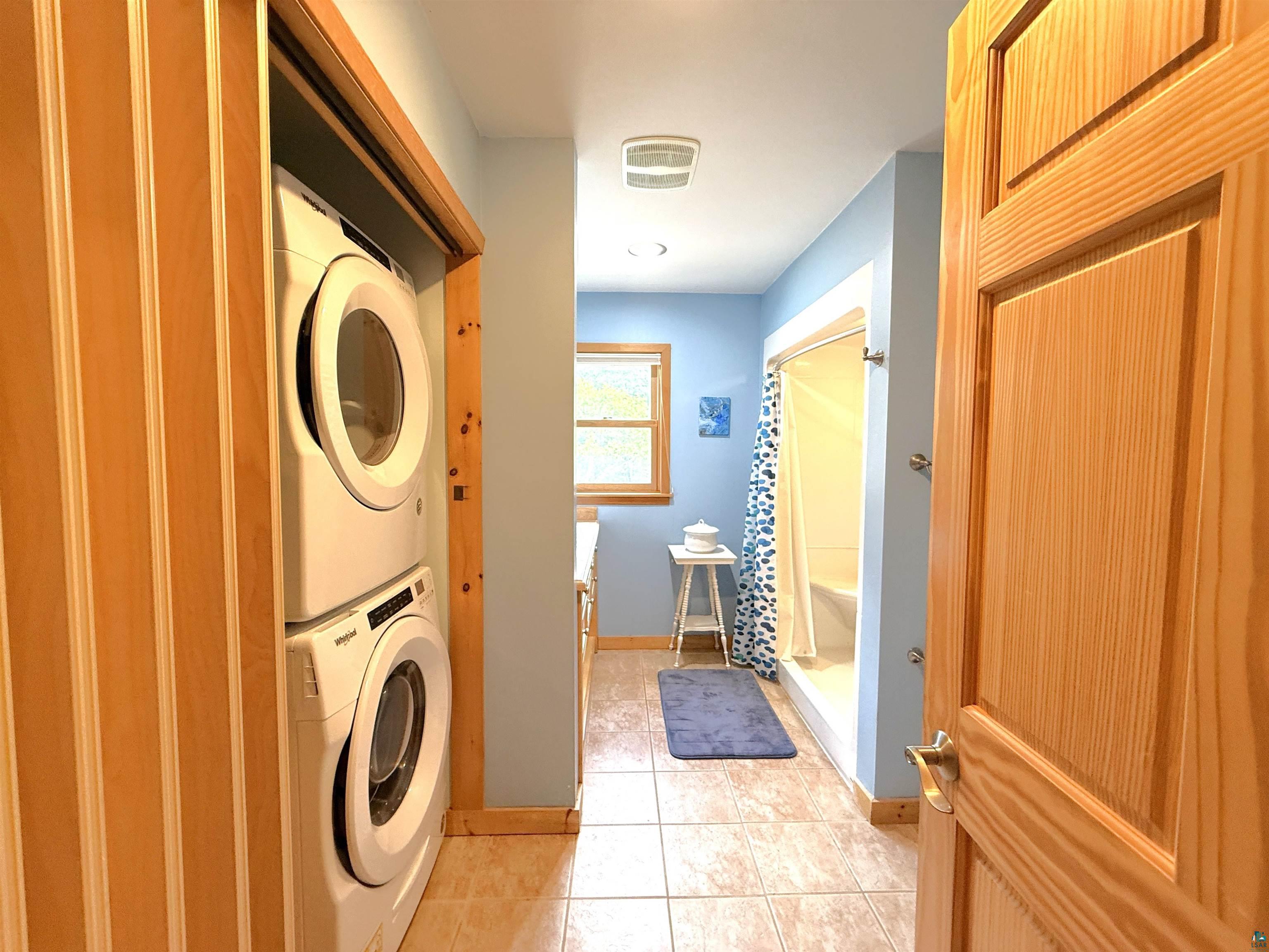 1787 North Bay Road Ely, MN 55731 - Photo 18 of 40 Laundry closet featuring a stacked washer and dryer, tile flooring, and light wood bi-fold doors