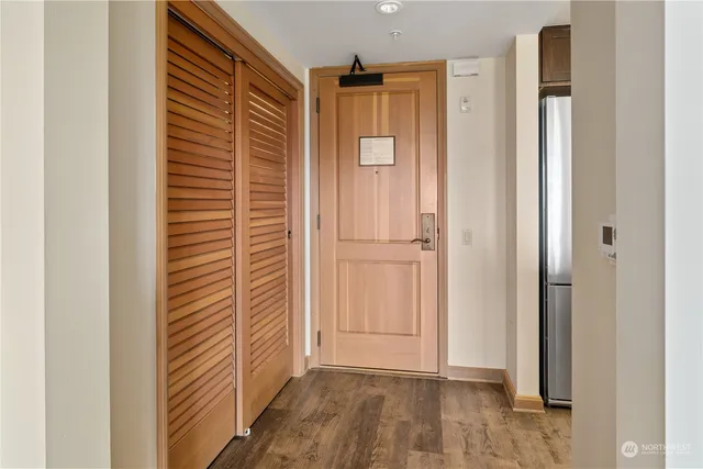 a view of a hallway with wooden floor and a bathroom