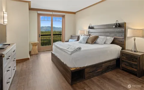 a spacious bedroom with a bed and wooden floor