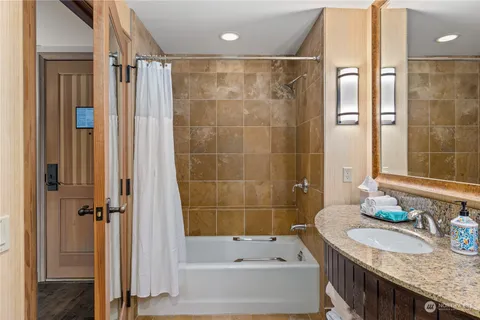 a bathroom with a granite countertop bathtub shower sink and vanity