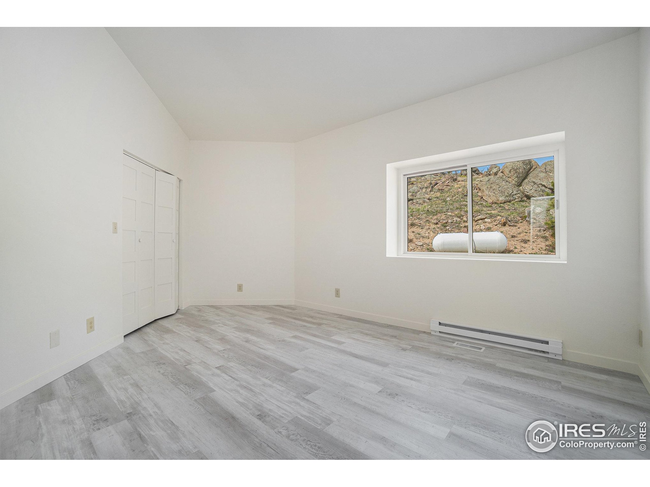 552 Blue Grouse Lane Bellvue, CO 80512 - Photo 12 of 39 a view of an empty room with wooden floor and a window
