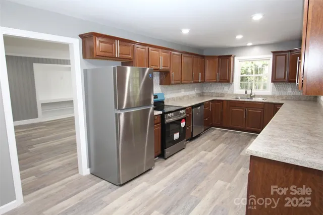 a kitchen with stainless steel appliances granite countertop a refrigerator and a sink
