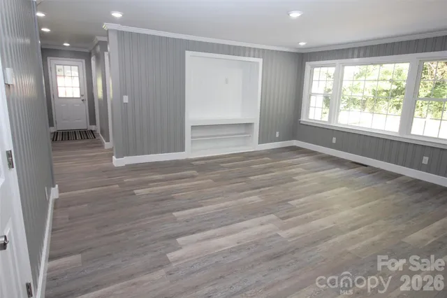 a view of a hallway with wooden floor and a living room